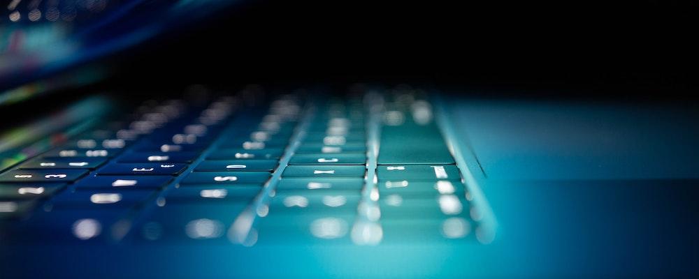Close up of a laptop keyboard in eerie blue light