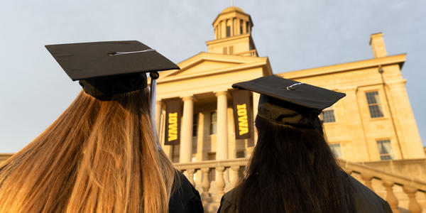 two graduates wearing caps with tassels standing in front of the capitol 