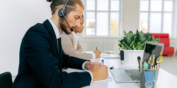 Picture of a man wearing a headset working on a laptop