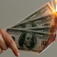 Hand holding 100 dollar bills that are on fire