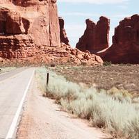 Vintage camper van driving down a desert highway toward rock formations